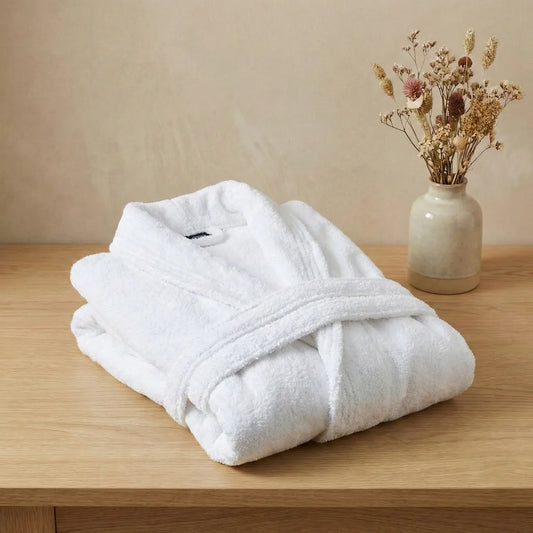 Primer plano del tejido de algodón peinado del albornoz blanco, mostrando su suavidad y acabado premium sin impurezas.