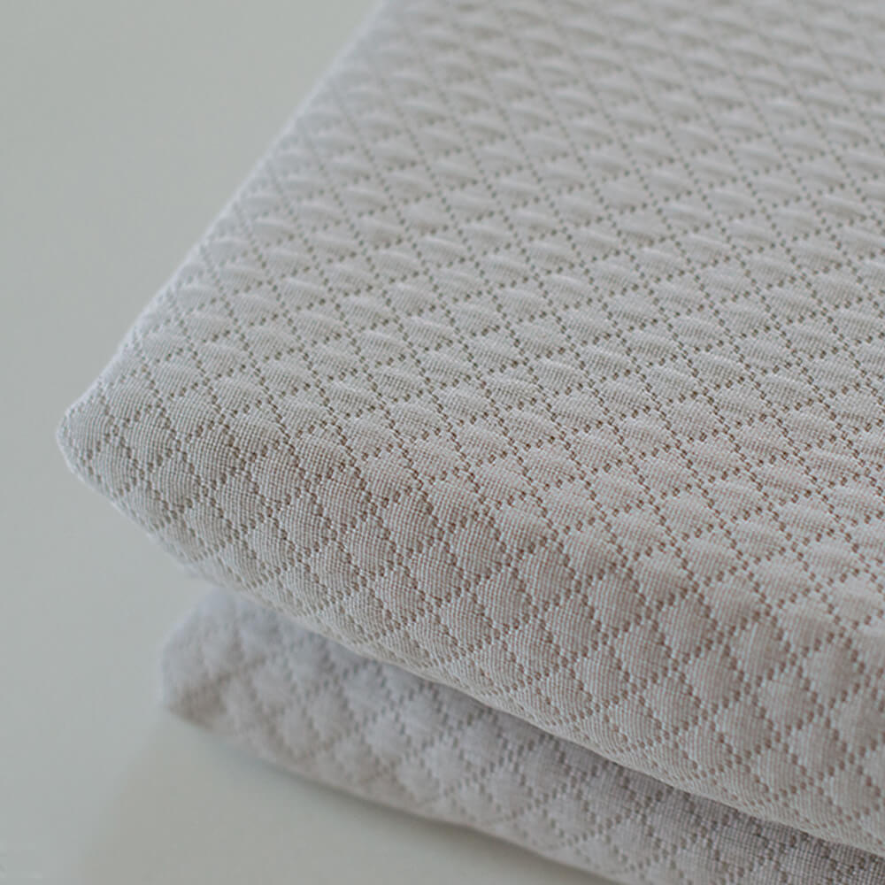 Colcha de retalhos geométrica com enchimento fino. Cor bege.