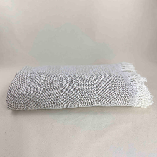 Colcha multiusos para sofá ou cama com franjas. Cor bege e cru.