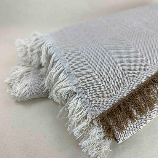 Colcha multiusos para sofá ou cama com franjas. Cor bege e cru.