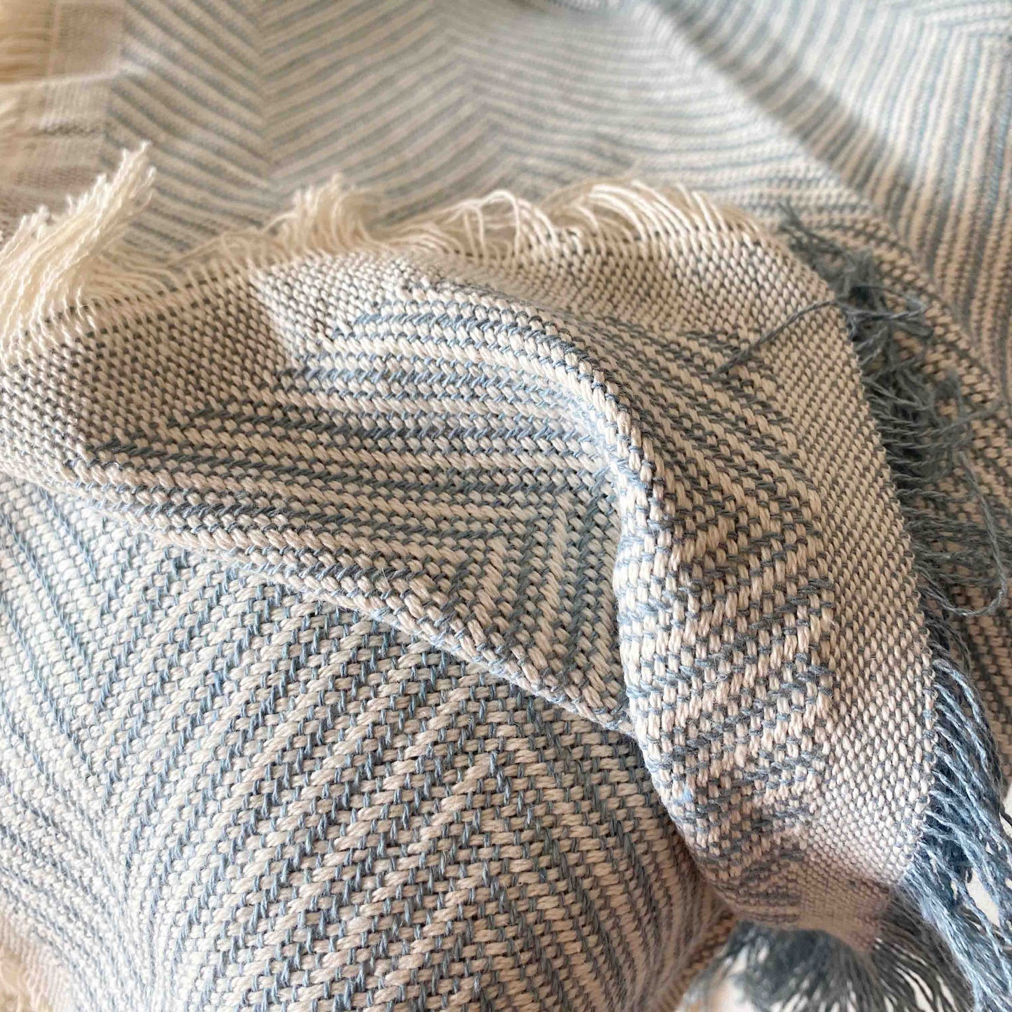Colcha multiusos para sofá ou cama com franjas. Cor bege e cru.