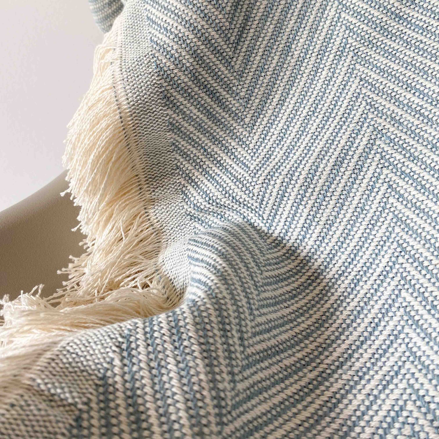Colcha multiusos para sofá ou cama com franjas. Cor bege e cru.