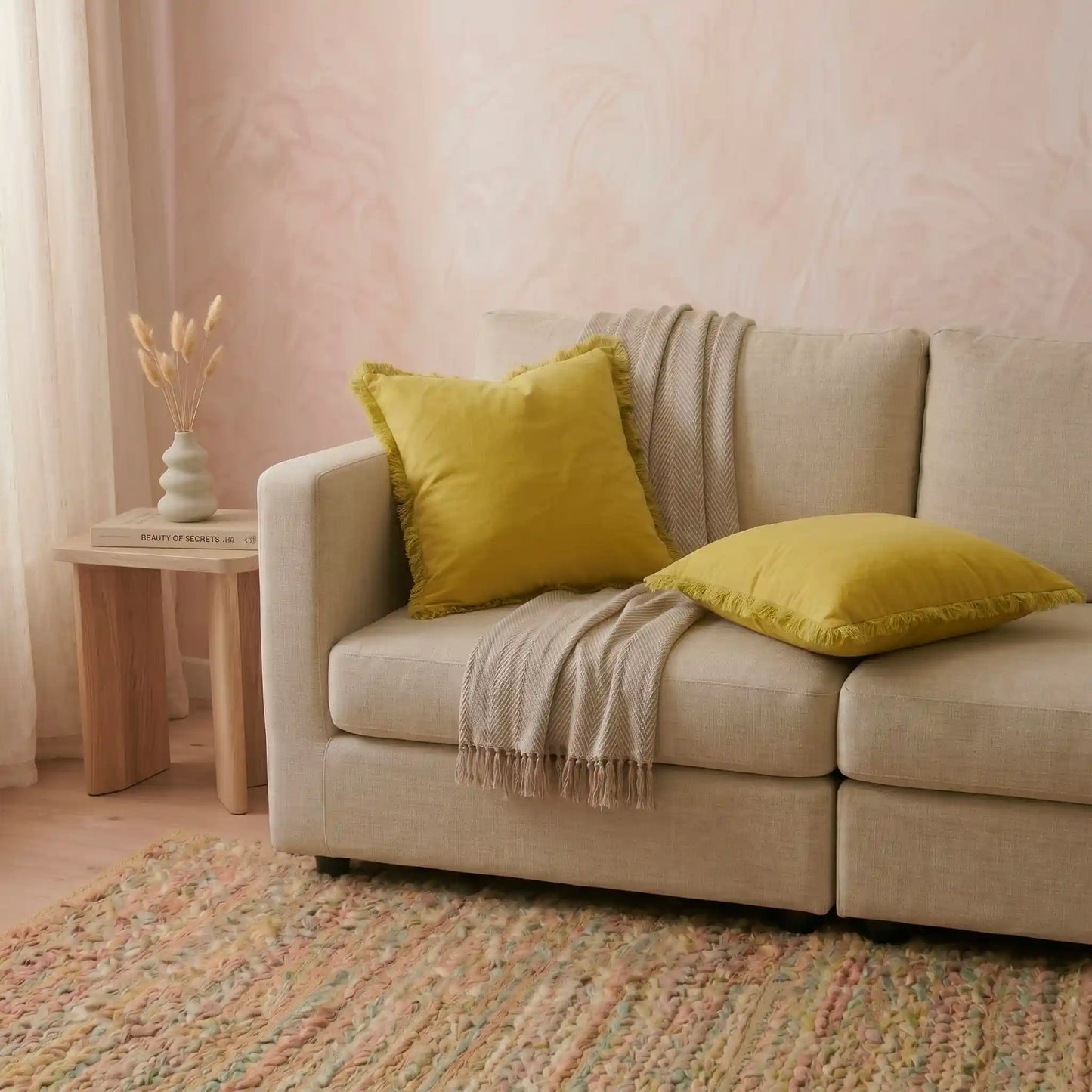 Combinación luminosa de cojines decorativos en el sofá, destacando la funda mostaza de algodón natural con flecos de Oma Home.