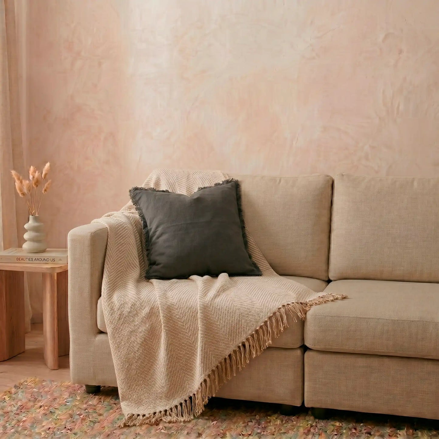Funda de cojín gris oscuro con flecos de Omahome decorando un sofá moderno, aportando carácter y contraste al salón.