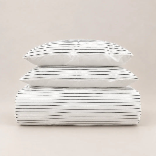 Edredão de inverno com design jacquard de riscas finas, dobrado de forma cuidada com duas fronhas a condizer.
