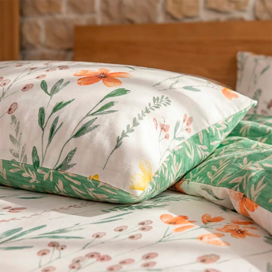 Funda de almohada a juego con estampado de flores amarillas y naranjas, tejido suave.