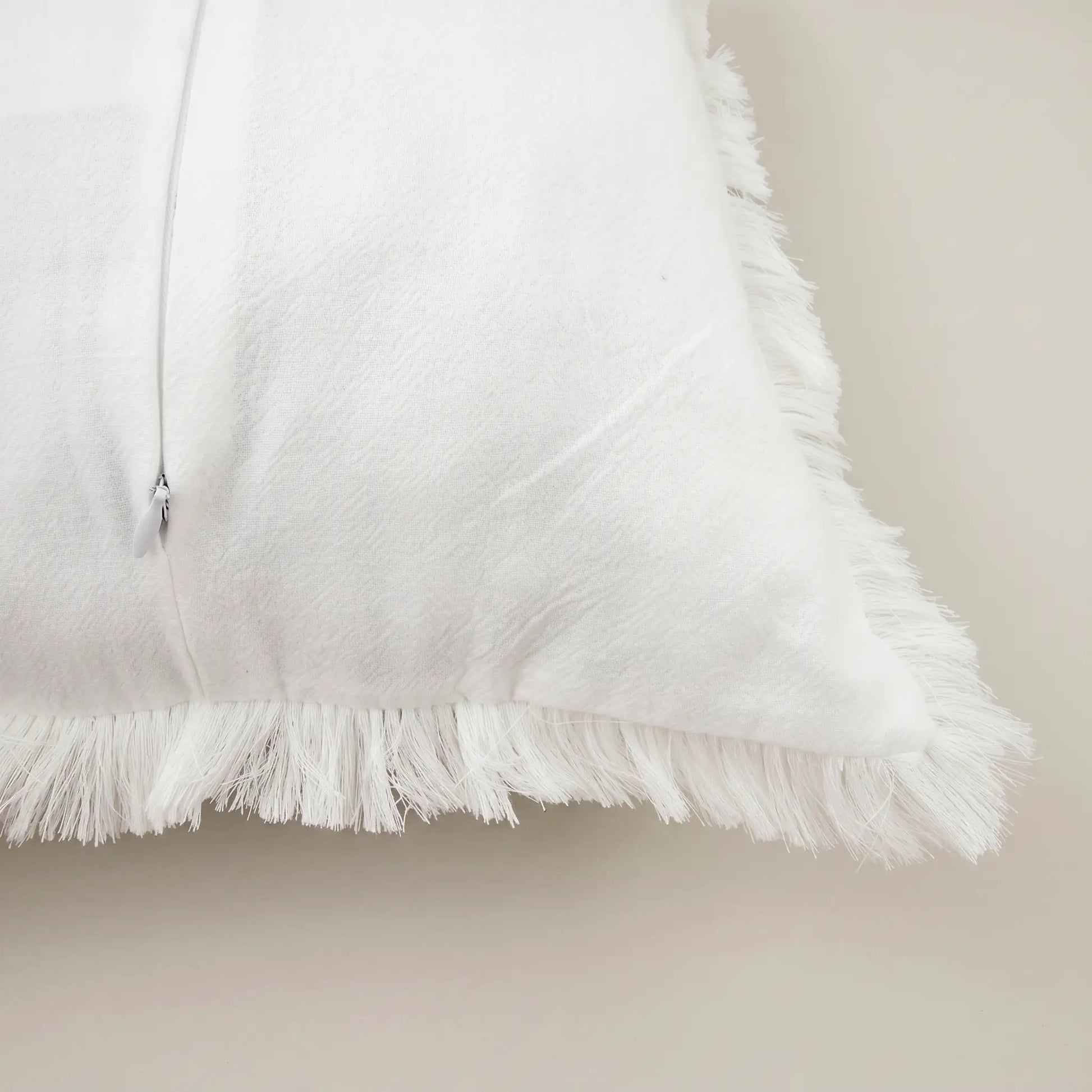 Primer plano del tejido extrasuave y transpirable 100% algodón de la funda de cojín blanca de Oma Home, destacando su pureza.