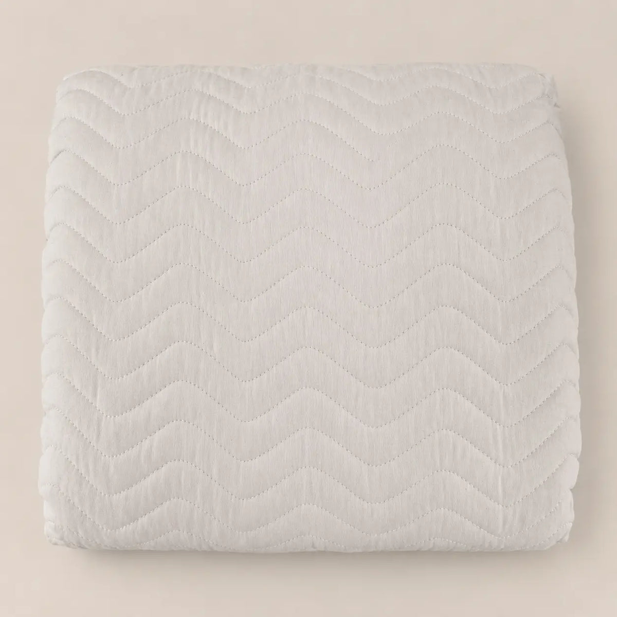 Plano cenital de la textura en relieve cosida en zig zag de la colcha neutra en microfibra suave.